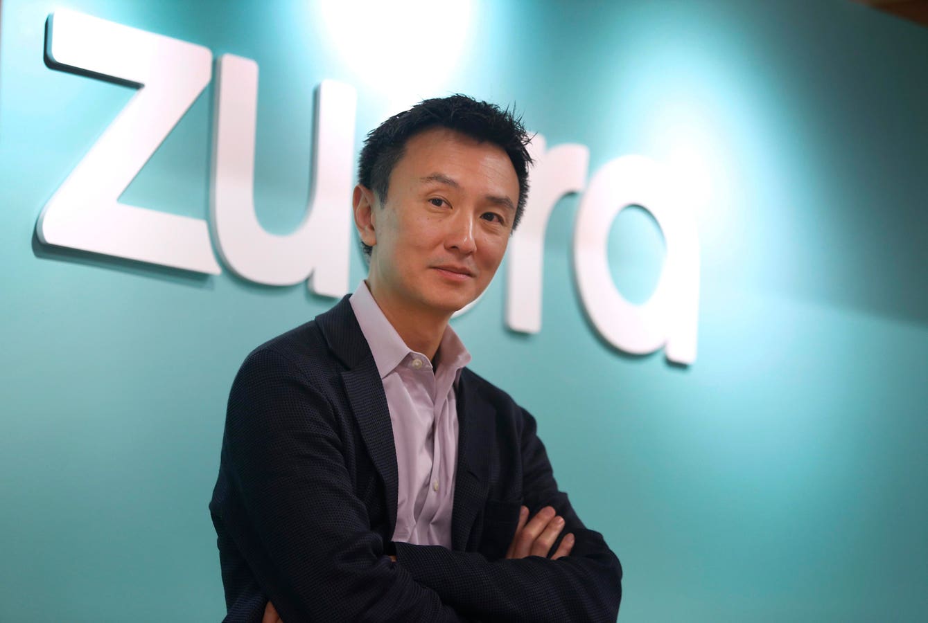 Zuora co-founder and CEO Tien Tzuo standing in front of the Zuora logo